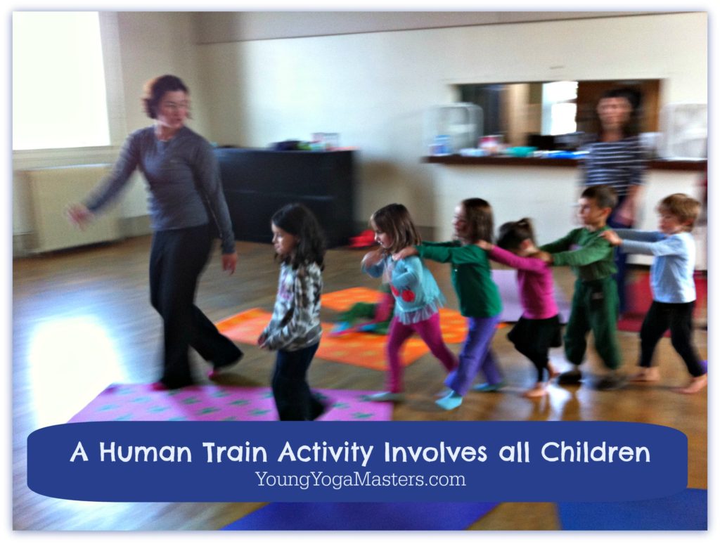 in kids yoga class, children form a human train by holding each others shoulders and walking