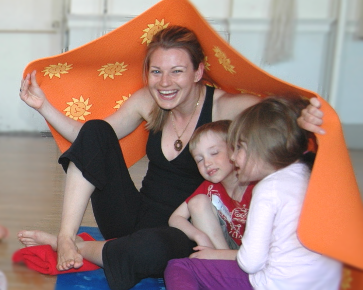 a teacher leading a playful yoga activity where the children hide under the mats in the kids yoga teacher training at Dovercourt House in Toronto Ontario Canada