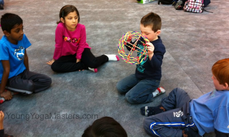 children pass a brething ball in a circle in kids yoga class to share their thoughts and feelings