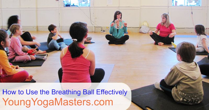 a kids yoga teacher demonstrates the breath by opening and closing a breathing ball.