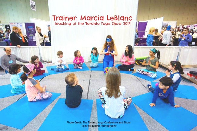 a yoga teacher dressed as a superhero leads a yoga class for children to save the world!