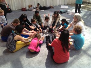 a group sits in a circle in yoga class making a wheel with their legs and arms pointing inwards and exploring the Chakras as wheels of energy through group yoga poses.