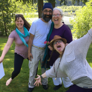 2 people jump into the picture making funny faces around Aruna and her husband who are laughing in the center of the picture.